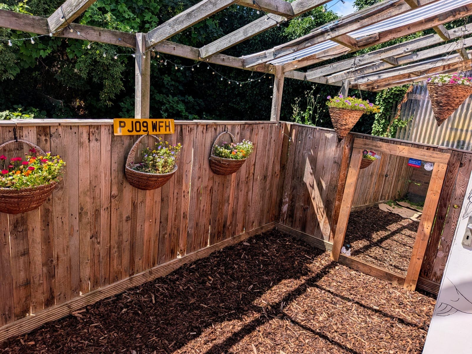 The studio's private garden — a pergola strung with lights over hanging baskets of flowers