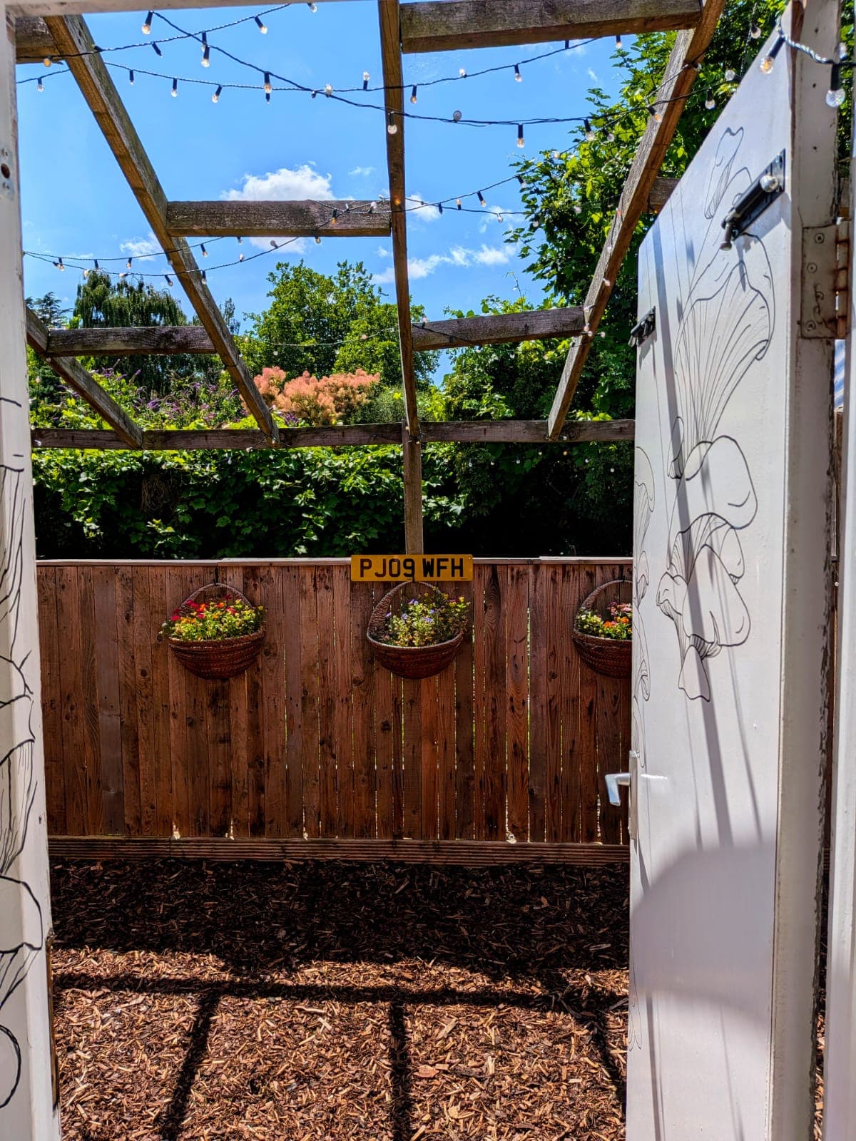 Open door leading out to the sunlit garden and pergola